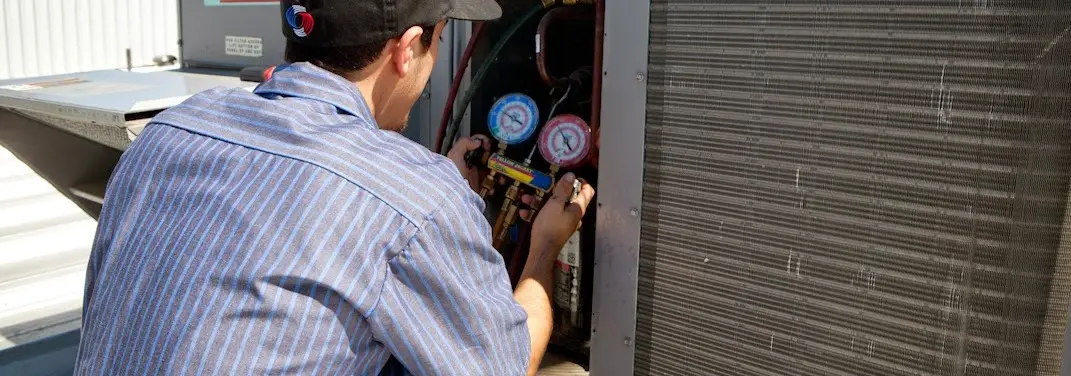 HVAC technician servicing a condenser unit in Reynolds