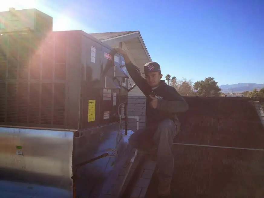 HVAC technician performing AC Tune-Up on a rooftop unit in Reynolds
